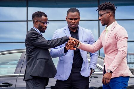 A group of three stylish African American businessman friends entrepreneurs fashion business suits...