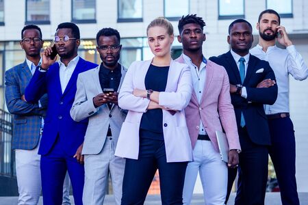 a group of seven successful business people businesslady and her male partners in stylish suits standing and looking proudly outdoors . teamwork and the multiethnic company conceptの写真素材