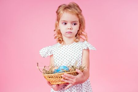 little blonde child with a chick cock easter in studio pink background.beautiful girl kid...