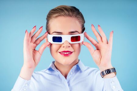 surprised amazed woman watching 3D movie in glasses in blue background in studio isolated