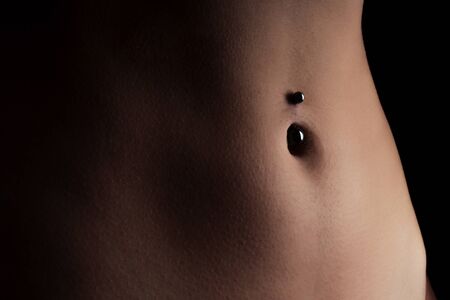 perfect female body Navel piercing erotic photoshoot on black background in studio shot