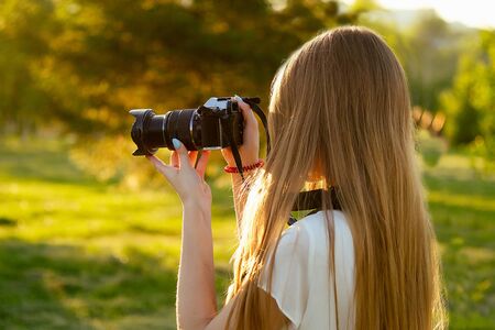 portrait of professional female photographer in the park photographing on a cameraの写真素材