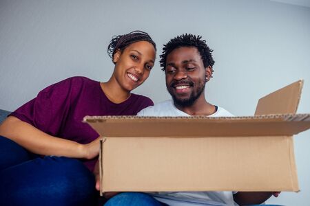 Bottom view of young fro american couple looking through the cardboard box on cat or dog insideの写真素材