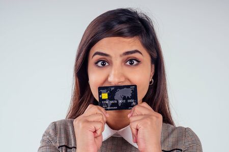 happy indian girl holding credit card in studio white backgroundの写真素材