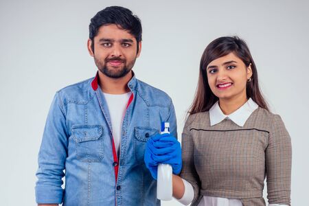 indian couple holding soap spray and latex gloves studio white backgroundの写真素材