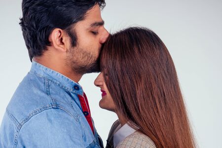 indian couple in love posing at studio white background.man kissing girls foreheadの写真素材