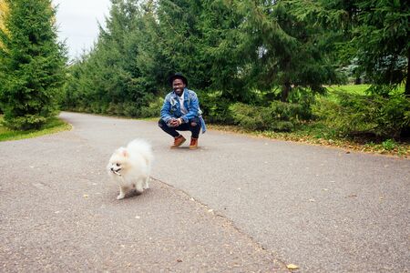 african american man walking in street with his fluffy spitz,teaching education dog teamsの写真素材
