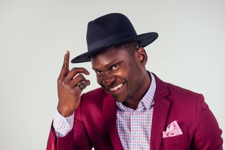 Retro style well dressed African american business man model in red suit and black hat in studio on...