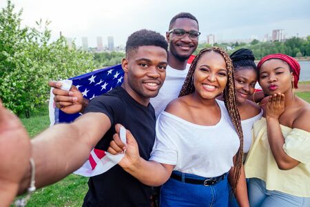 Group of girls and boys smiling with American flag in spring park autumn evening learning English...