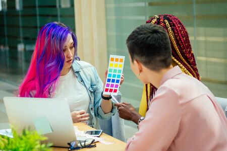 mixed-race creative business:afro american female with cool pigtails dreadlocks sitting together with caucasian short haircut feminist asian girl and european designer multi-colored long haired.の写真素材