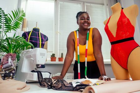 beautiful african american tailor woman sewing laces sexy lingerie in showroomの写真素材