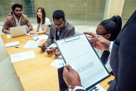well-dressed business afro american men making a report to subordinate employees in a modern office
