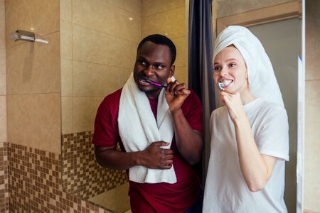 african american man and woman with a towel wrapped on her head together clean teethの写真素材
