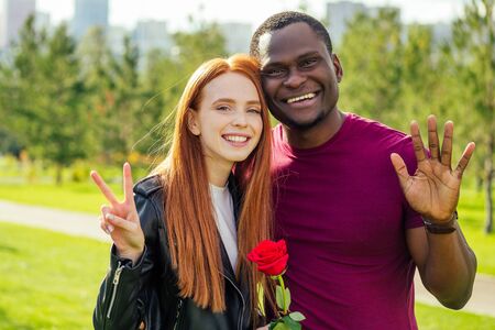 Close up of interracial couple holding white rose in spring autumn park