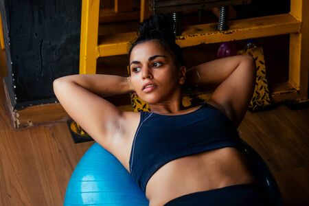 indian woman doing pilates and balance exercises gymnastic ball