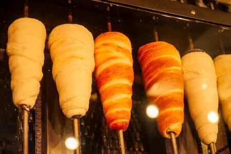 woman with an appetite eats a traditional Czech sweet Trdelnik in Prague street.