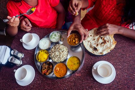 beautiful mother and happy father eating thali with daughter in cafe and drinking masala teaの写真素材