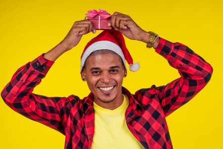 latin hispanic santa men showing gifts box in yellow wall studioの写真素材