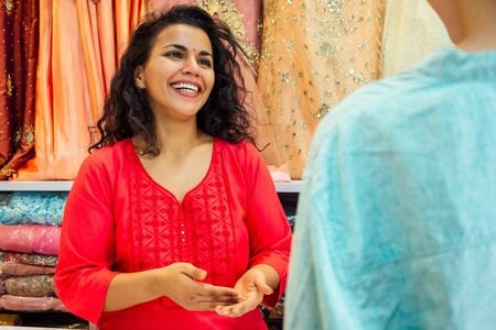 indian seller women in red kurta stand in her studio showroom