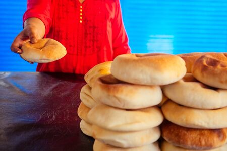 happy indian female salling fresh traditional buns in bazar .