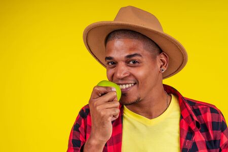 latin hispanic farmer showing a green apple in studio yellow background