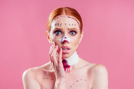 Patient in bandages. Nurses and young woman in studio pink backgroundの写真素材