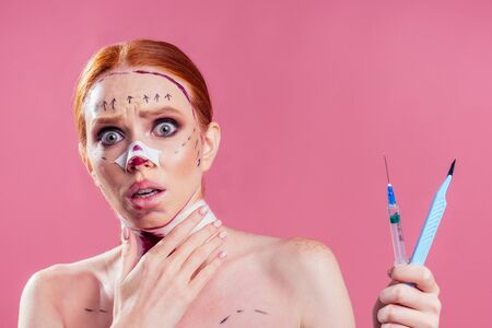 caucasian panic female cosmetic lifting procedure in studio pink backgroundの写真素材