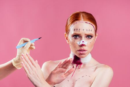 Patient in bandages. Nurses and young woman in studio pink backgroundの写真素材