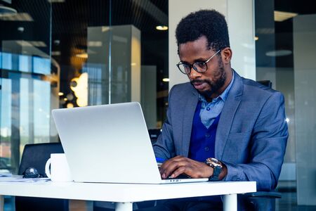 Handsome cheerful african american in a modern office with a panoramic window.の写真素材