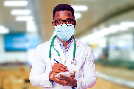 happy male african medical surgeon infectious disease specialist doctor in a white coat on a background hospital lights .epidemic corona virus preventionの写真素材