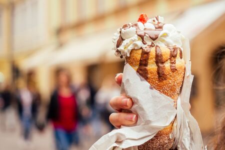 appetite eats a traditional Czech sweet Trdelnik with vanilla cream and strawberries in Prague...