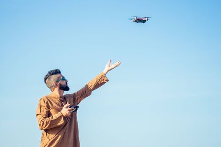 arabian man testing a drone photo and video shooting on quadrocopter over the sea in Goa beach