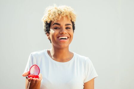 Proposal of a african american woman asking marry to a man at white studio background
