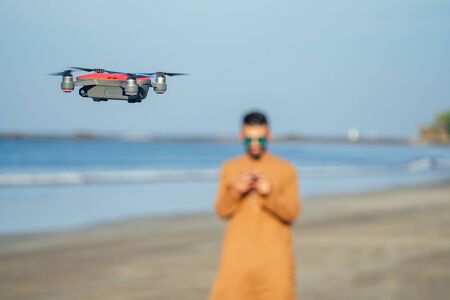 arabian man testing a drone photo and video shooting on quadrocopter over the sea in Goa beach