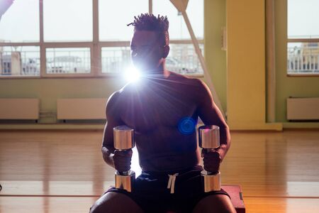 afro holding dumbbells workout for abc press and hands in gym windows background