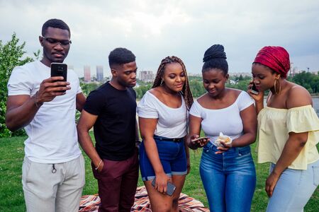 group of five friends female and male taking selfie on camera smartphone and having fun outdoors...