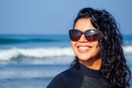 cute indian woman wearing sun black glasses and wetsuit on Goa beach
