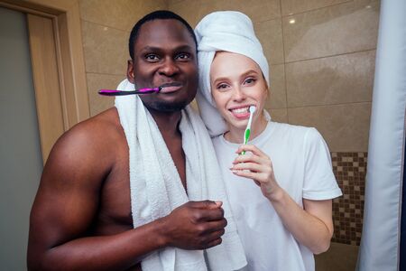 african american man and woman with a towel wrapped on her head together clean teethの写真素材
