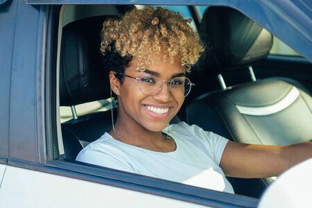 cheerful young african american latin girl showing her new car key at dealershipの写真素材