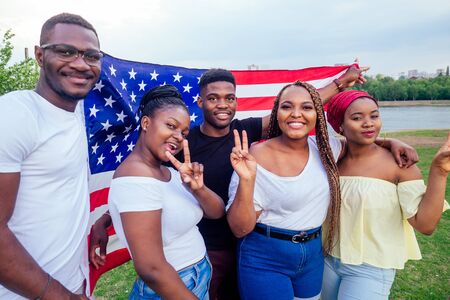 Group of girls and boys smiling with American flag in spring park autumn evening learning English language exchange studentsの写真素材