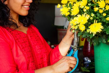 cheerful young woman brunette florist selling flowers in a flower shopの写真素材