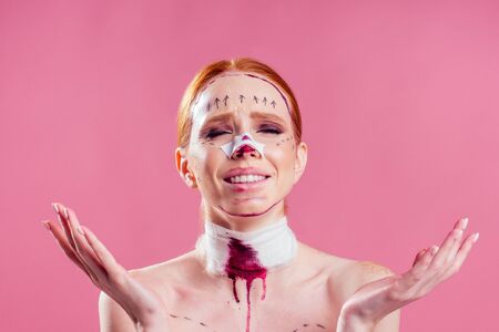 Patient in bandages. Nurses and young woman in studio pink backgroundの写真素材