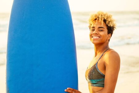 african american surfer girl in water enjoying sunsetの写真素材