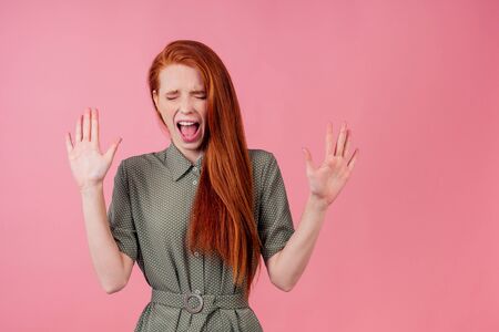 redhair ginger woman amazed and surprised in cotton green white peas dress in pick background studioの写真素材