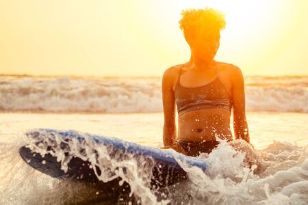 brazilian american woman with board at sunset feeling relax