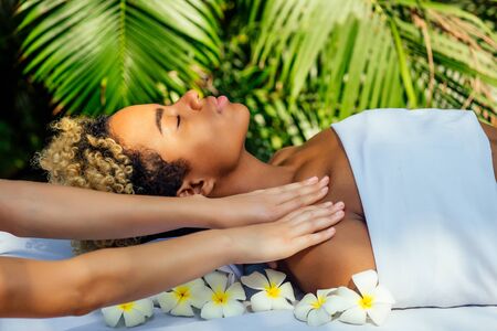 brazilian woman getting back and shoulders massaging in outdoor spa Ayurveda centre in India green tropical backgroundの写真素材