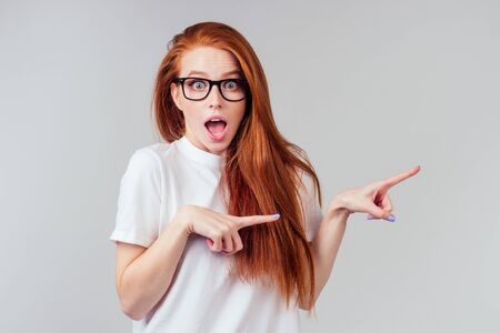 redhaired ginger woman feeling happy ,wearing white cotton t-shirt in gray studio backgroundの写真素材