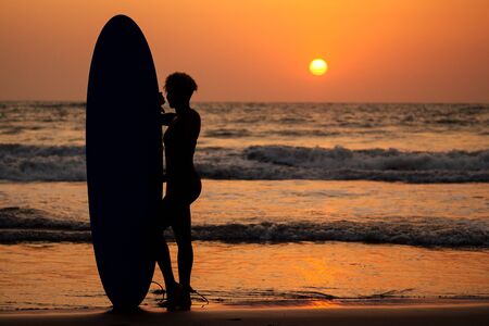 afro american woman run with surfboard on beach in Goa.の写真素材