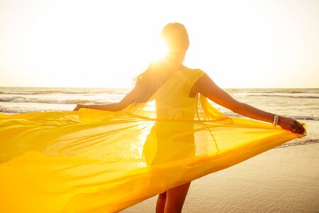 woman in amazing yellow dress feeling free and happy yo be at ocean.の写真素材