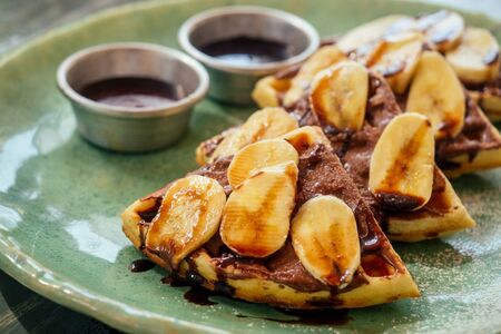 Belgian waffles with banana and chocolate topping .の写真素材